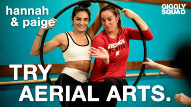 Two women in athletic wear with an aerial hoop.
