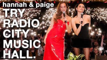 Two women in formal attire holding microphones on stage.